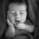 newborn photography singapore baby wrapped up and smiling portrait black and white